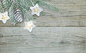 Snowy christmas tree branch and star lights garland on wooden background