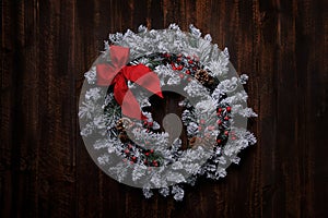 Snowy Christmas Wreath on a Wooden Background With Red Bow