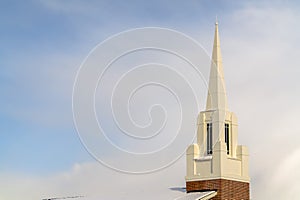 Snowy church steeple and roof against cloudy sky