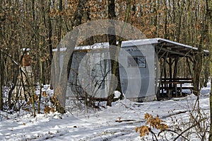 Snowy cosy nook with wooden shelter for winter relaxation with friend in the deciduous forest
