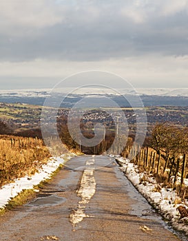 A snowy country road looking towards snow covered moors in the background