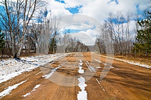 Snowy dirt road on a beautifully sunny winter day with bright blue skies with puffy clouds - in the Sax-Zim Bog nature area in Nor
