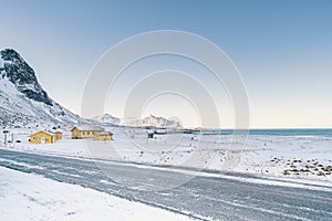 Snowy empty road along the sea & shoreline in the white cold world of north Norwegian islands.