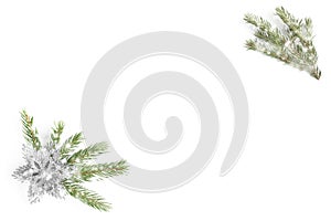 Snowy fir tree branch and silver glitter flower or star on white background. Isolated. Top view with copy space. Flat lay.