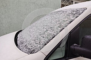 A snowy and frosty white car in winter. Snow on the windshield