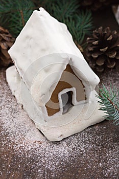 Snowy Gingerbread house with snowflakes christmas tree and globe on stone wall background. Homemade christmas cookies - gingerbrea