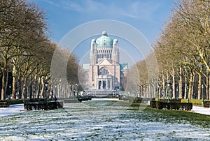 Snowy grass and bare trees leading to the Basilica of Koekelberg