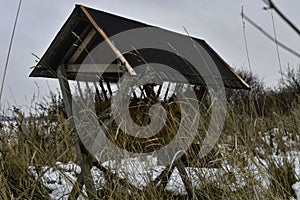 A snowy hay rack in winter. Feeding rack filled with hay and ready for winter feeding of game animals. Concept of the