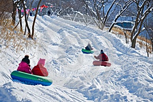 snowy hillside transformed into a thrilling tubing course, where children slide down the slope on inflated tubes