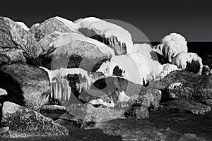 Snowy and icy rocks in the ocean. Black and white