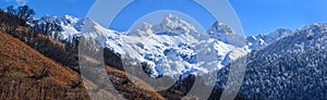 Snowy Kardyvach mountain peak under blue sky. Scenic sunny autumn winter panorama landscape. Sochi, Russia, Caucasus mountains