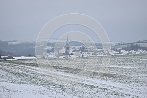 snowy landscape in the Eifel with the village Welling in a valley photo