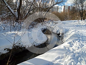 Snowy landscape of the nonfreezing Ramenka river in the winter evening. Moscow. Russia.