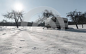 Snowy landscape at sunrise in an orchard with a camper van