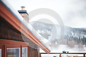 snowy mountain cabin roof with chimney, smoke merging with fog