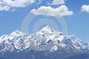 Snowy mountain peak against a blue sky with white clouds. Mountain landscape of the rocky mountain.