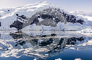 Snowy mountain peak and the glacier reflected in the Antarctic waters of Neco bay