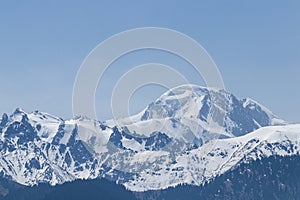 Snowy mountain peak on a sunny day with avalanches on the slope
