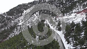 Snowy mountain switchbacks. Mountain peaks in snow with empty car road and pine tree forest. Epic mountain landscape