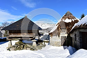 Snowy mountain village with ancient palloza houses made with stone and straw and galician granary horreo. Piornedo, Lugo, Spain.