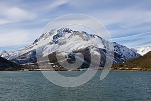 Snowy mountain with a village at the base next to embalmed water