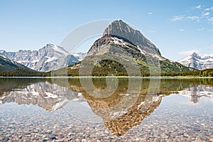 A snowy mountain water reflection on Swiftcurrent Lake in Many Glacier region of Glacier National Park, Montana. Grinnell Point, a