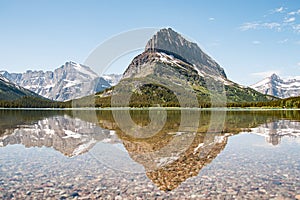 A snowy mountain water reflection on Swiftcurrent Lake in Many Glacier region of Glacier National Park, Montana. Grinnell Point, a photo