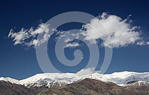 Snowy Mountains against Dark Blue Sky with White Clouds