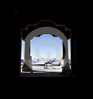 Snowy mountains through a buddhist monastery door