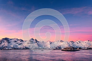 Snowy mountains and colorful sky reflected in water at sunset