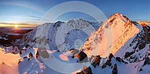 Snowy mountains under orange sunset sky