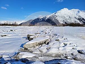 Snowy mudflats with visible ice churn, Turnagain Arm, outside of Girdwood, Alaska on a clear winter day.