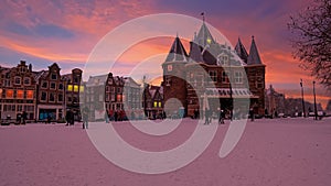 Snowy Nieuwmarkt with the Waag building in the city center from Amsterdam in the Netherlands at sunset