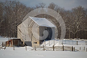 Snowy old barn with diagonal boards and barnyard