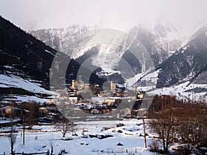 Snowy Old towers (Svan towers) and houses at the foot of the mountain, in winter. Mestia, Georgia