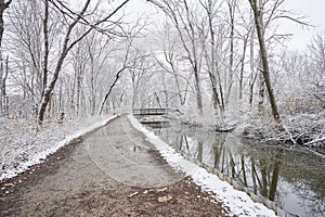 Snowy path alongside canal with bridge
