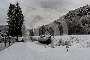 A snowy path with a tree between the fence and the train tracks