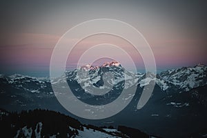 Snowy peaks of cliffs under a cloudy sky during a sunset