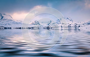 Snowy peaks reflected in the calm waters of Sandvika bay.