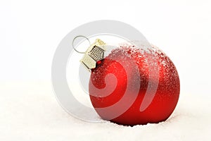 Snowy red christmas matt ball standing on snow on white background photo