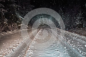 Snowy road at night in the forest, spruce and trees under the snow, winter night