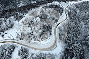 Snowy road runs in the forest in the mountains through the pass in December. A car driving through the winter snowy