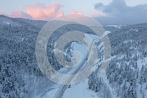 Snowy road runs in the forest in the mountains through the pass in December. A car driving through the winter snowy