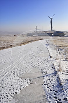 Snowy road with wind turbines and Street lamps powered by solar panels and wind turbine