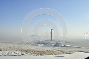 Snowy road with wind turbines and Street lamps powered by solar panels and wind turbine