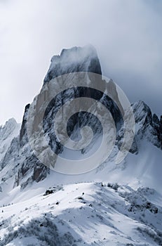 a snowy, rugged mountain peak surrounded by clouds, conveying a serene yet formidable atmosphere