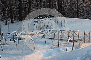 Snowy scene with garden beds covered with inches of deep snow and ice, signs that it`s still Winter