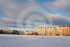 Snowy soccer field outdoors. Residential homes around. Spring sunny day with blue sky
