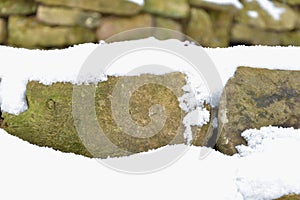 Snowy stone wall. Stones covered with snow.