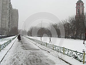 Snowy street with people traces, building and orthodox church